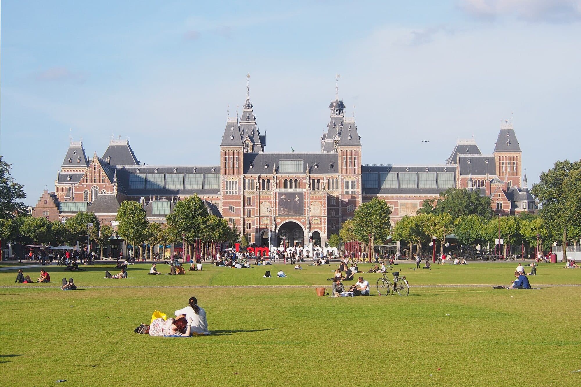 People on the lawn of Museumplein with the Rijksmuseum behind them